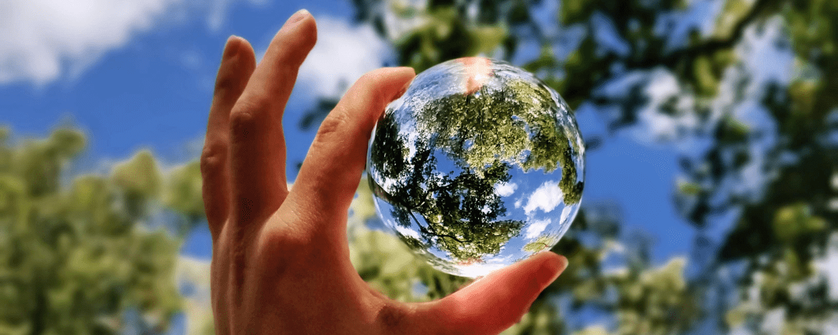 Hand holding glass orb representing sustainability and the Earth.